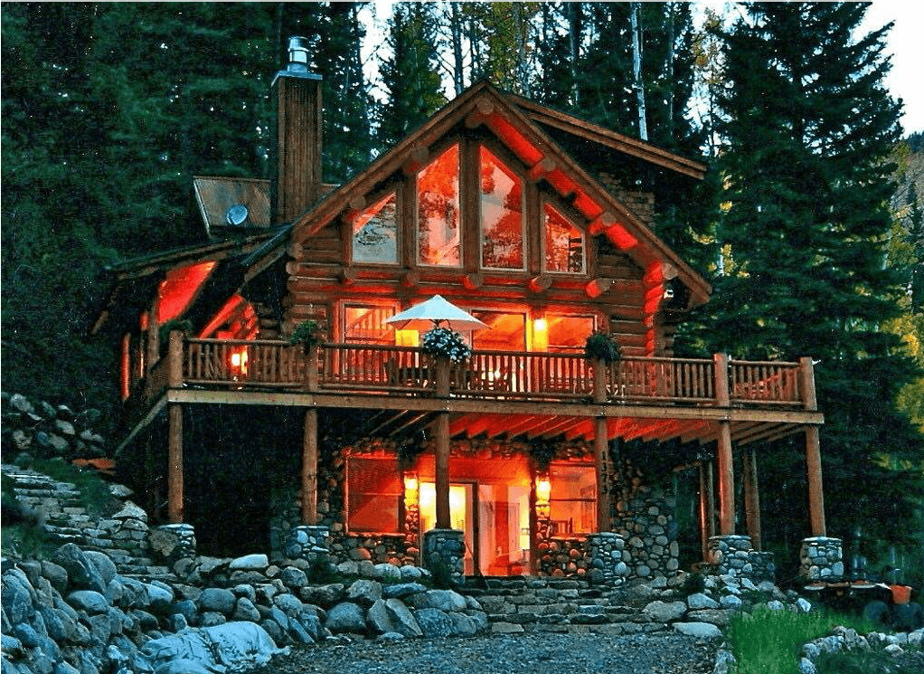 View Of Cabin In The Forest With Lights On