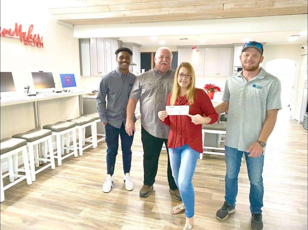 three men and a woman with a check