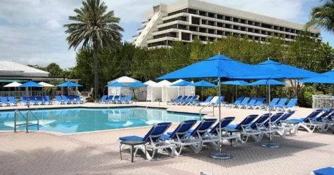 A swimming pool with blue umbrellas and lounge chairs.